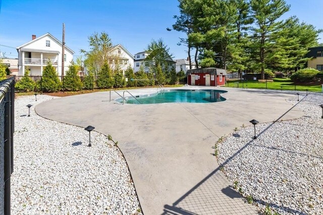 pool with fence, a storage unit, a patio, and an outbuilding