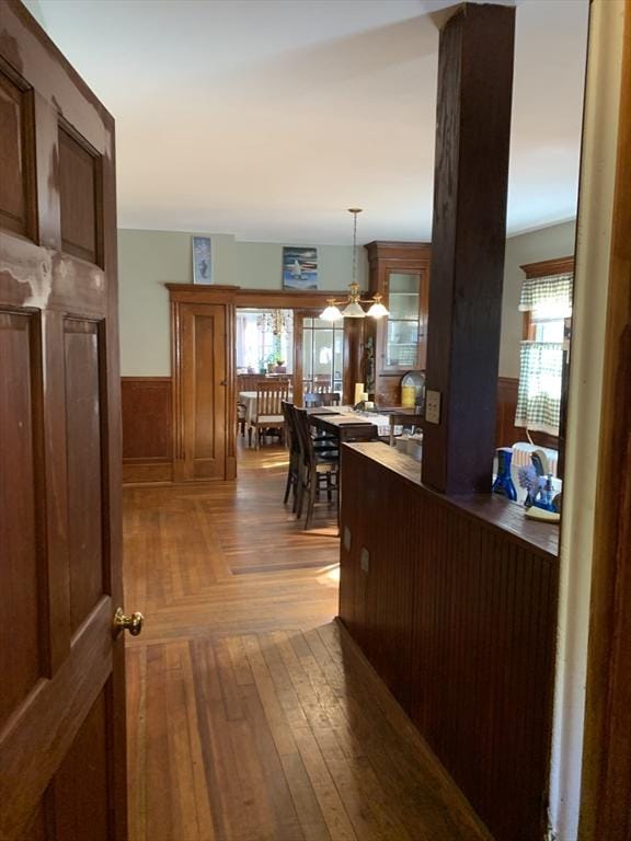 interior space with a wainscoted wall, parquet flooring, and a chandelier