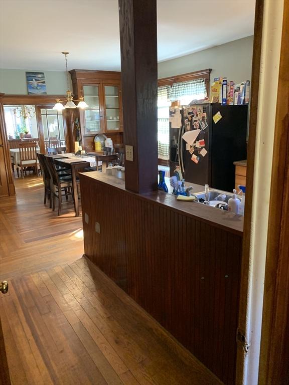 kitchen featuring glass insert cabinets, parquet flooring, freestanding refrigerator, and pendant lighting