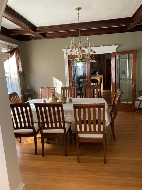 dining room featuring a notable chandelier, light wood-style flooring, coffered ceiling, and beam ceiling