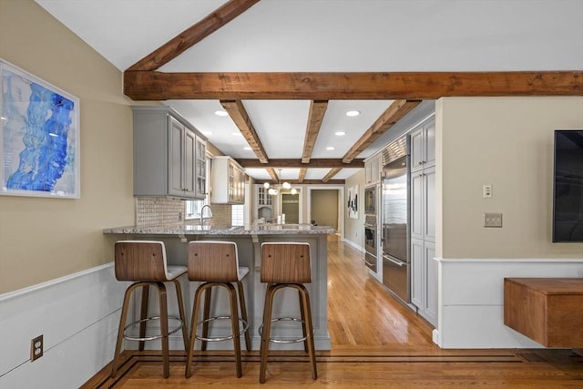 5 John Matthew Rd, Hopkinton, MA 01748 - kitchen featuring a peninsula, beamed ceiling, gray cabinets, light wood-style floors, and a breakfast bar area