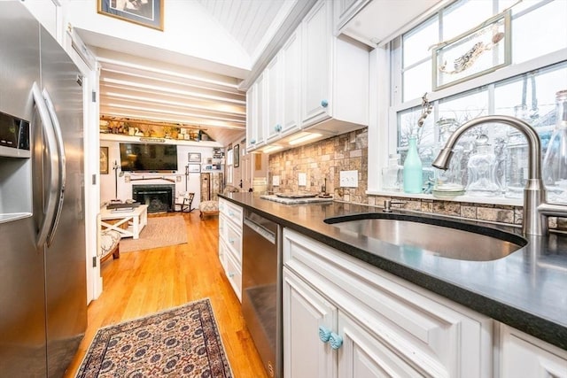 kitchen featuring dark countertops, a fireplace, appliances with stainless steel finishes, and a sink