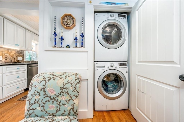 washroom featuring stacked washing maching and dryer, light wood-style flooring, and laundry area