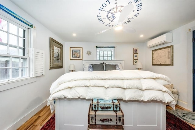 bedroom with wood finished floors, baseboards, a wall unit AC, and recessed lighting