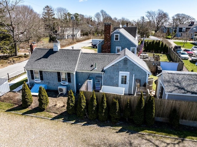 exterior space with roof with shingles, fence, a chimney, and a residential view