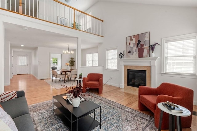 32 Old Framingham Rd Unit 20, Sudbury, MA 01776 - living area with light wood-style flooring, a tile fireplace, a chandelier, and a high ceiling