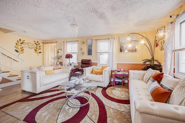 living area featuring stairs, a textured ceiling, a chandelier, and wood finished floors
