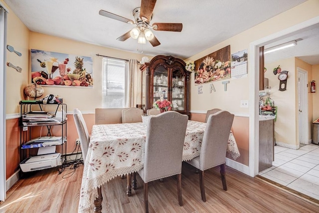 dining space with baseboards, a ceiling fan, and wood finished floors