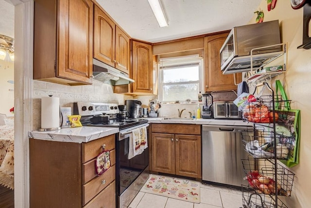 kitchen with brown cabinetry, appliances with stainless steel finishes, and under cabinet range hood