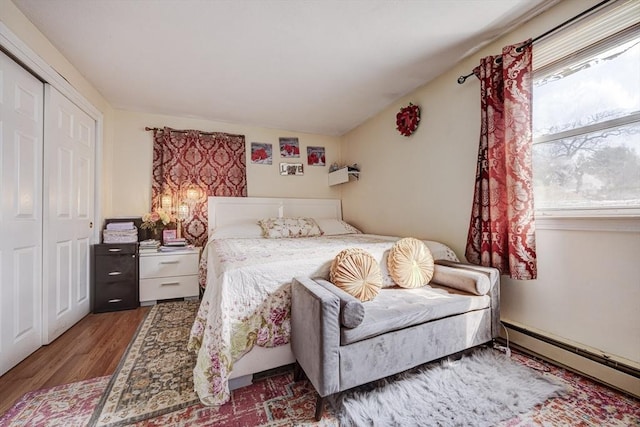bedroom featuring a closet, a baseboard radiator, and wood finished floors