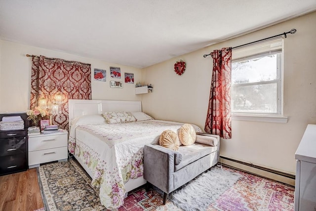 bedroom with wood finished floors and baseboard heating