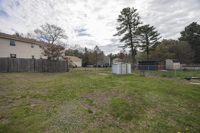 view of yard with a fenced backyard, an outbuilding, and a shed