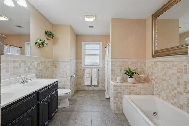 3 Birch Ave, East Longmeadow, MA 01028 - bathroom with tile walls, a bath, toilet, a wainscoted wall, and double vanity