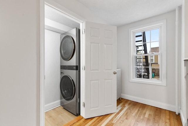 laundry room with light hardwood / wood-style floors and stacked washer / dryer