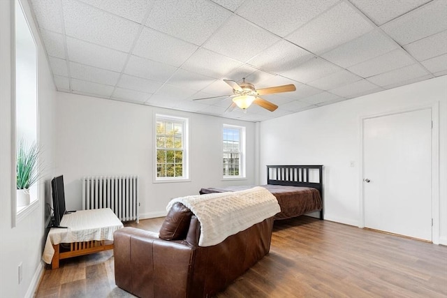 bedroom featuring a paneled ceiling, ceiling fan, radiator heating unit, and hardwood / wood-style floors