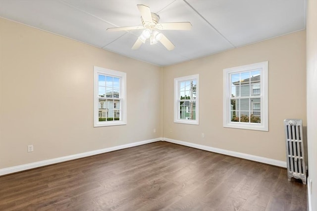 spare room featuring ceiling fan, dark hardwood / wood-style flooring, and radiator heating unit