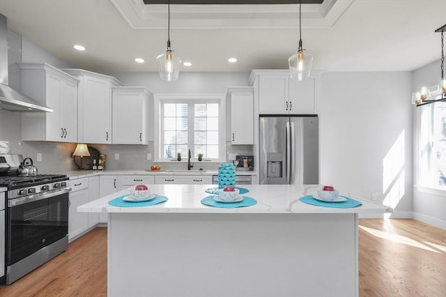 117 Montvale Ave, Woburn, MA 01801 - kitchen with stainless steel appliances, wall chimney range hood, a sink, white cabinetry, and decorative backsplash