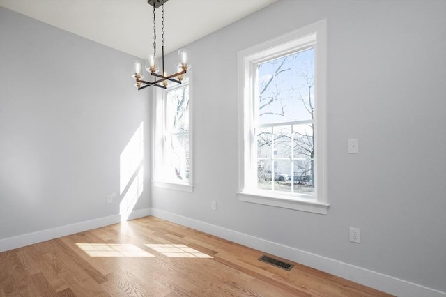 117 Montvale Ave, Woburn, MA 01801 - unfurnished dining area with a chandelier, baseboards, and light wood-style flooring