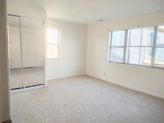 unfurnished bedroom featuring multiple windows, carpet flooring, and baseboards