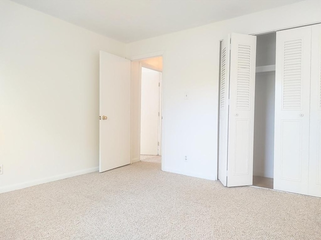 unfurnished bedroom with carpet, a closet, and baseboards