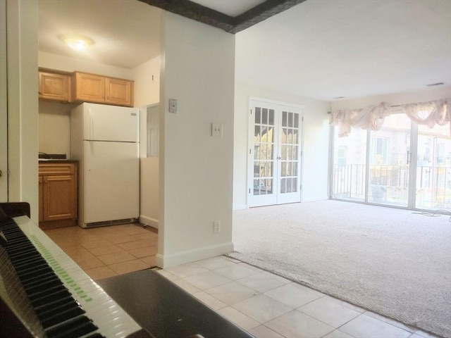 kitchen featuring freestanding refrigerator, light carpet, light tile patterned floors, and baseboards