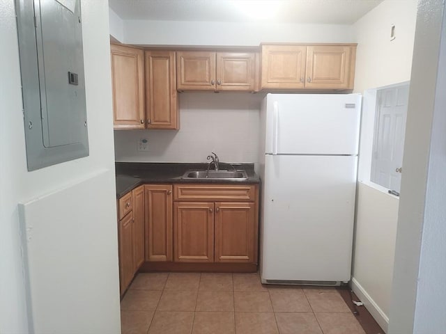 kitchen featuring freestanding refrigerator, a sink, electric panel, dark countertops, and light tile patterned flooring
