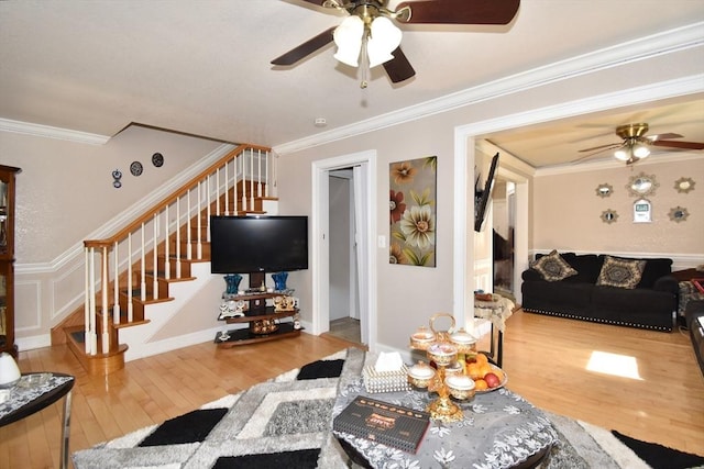 living room featuring stairs, a ceiling fan, hardwood / wood-style flooring, and ornamental molding