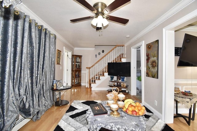 entryway featuring stairway, wood finished floors, ceiling fan, and crown molding