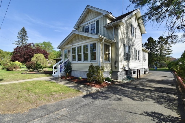 view of front of property featuring asphalt driveway and a front lawn