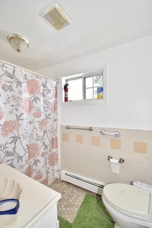 full bath with a baseboard heating unit, toilet, tile walls, a shower with shower curtain, and wainscoting