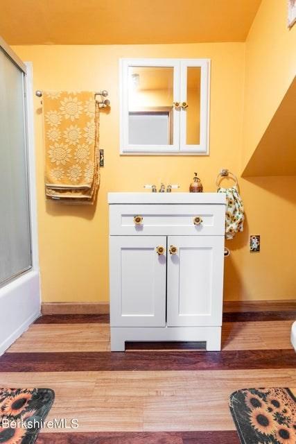 bathroom featuring hardwood / wood-style flooring, shower / bath combination with glass door, and vanity