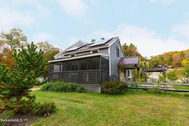 back of property featuring a lawn, solar panels, and a sunroom