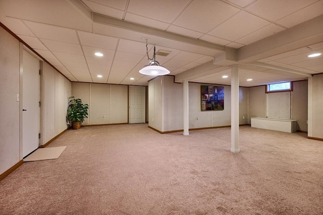 basement featuring a paneled ceiling and light colored carpet