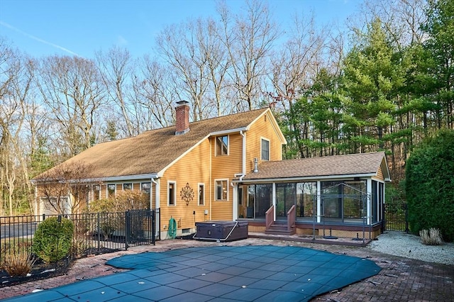 back of house with a sunroom, a swimming pool with hot tub, and a patio