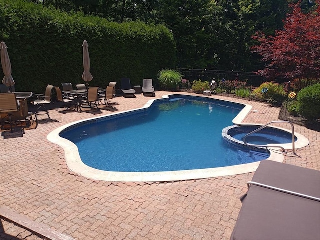 view of swimming pool featuring an in ground hot tub and a patio area