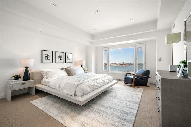 bedroom with a water view and carpet flooring