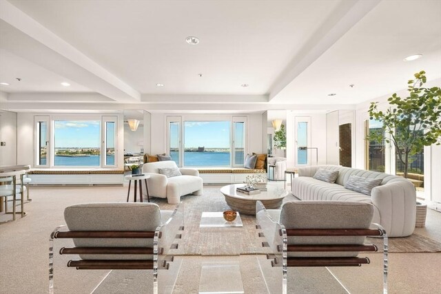 living room featuring light carpet, a water view, beamed ceiling, and plenty of natural light