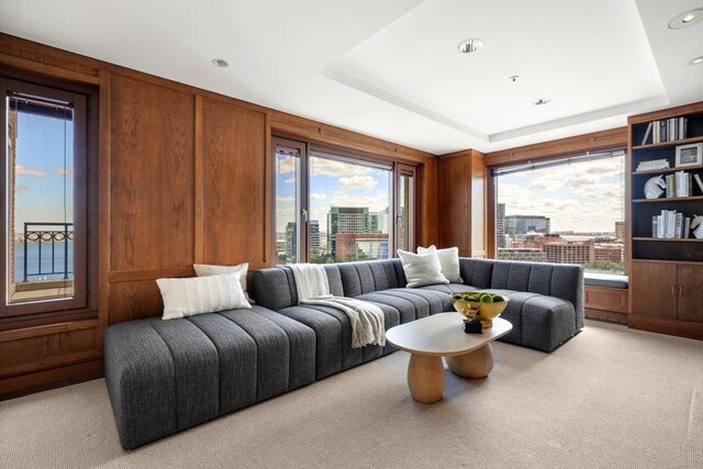 carpeted living room featuring wooden walls and a raised ceiling