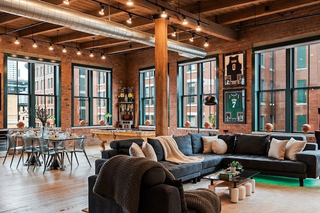 living room with wood ceiling, rail lighting, beam ceiling, brick wall, and wood-type flooring