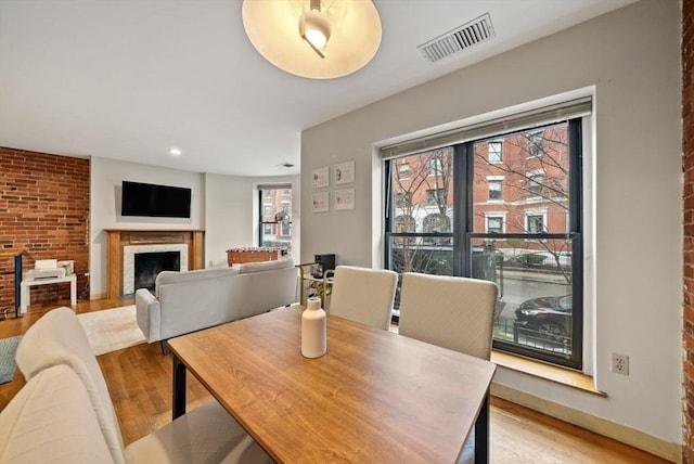 dining area featuring light wood-style flooring, a fireplace, visible vents, and baseboards