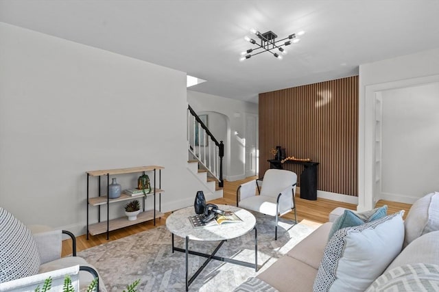living room featuring a notable chandelier, baseboards, wood finished floors, and stairs