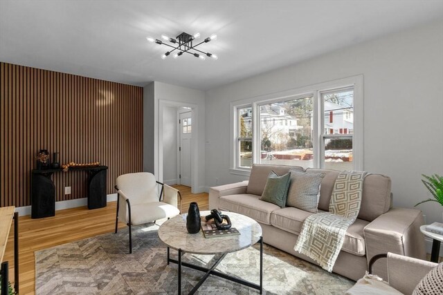 living room featuring an inviting chandelier, light wood-style floors, and baseboards