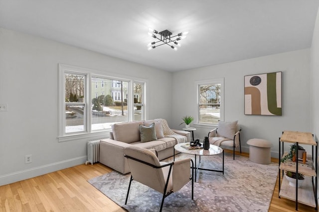 living area featuring plenty of natural light, wood finished floors, baseboards, and a chandelier