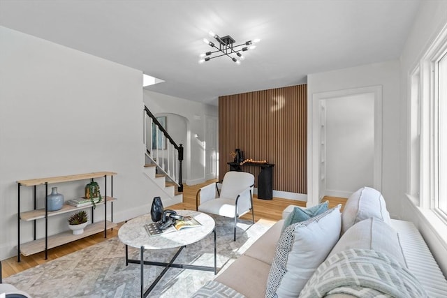 living room with baseboards, wood finished floors, an inviting chandelier, and stairway