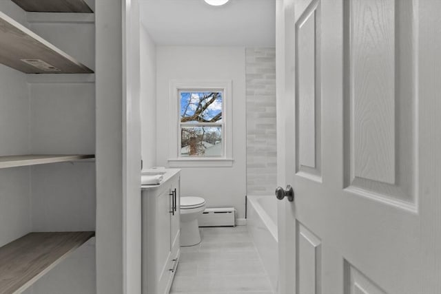 bathroom featuring vanity, toilet, baseboard heating, and a bathing tub