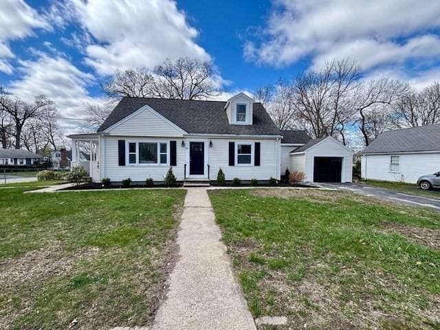 view of front of home with driveway, an outbuilding, a detached garage, and a front yard