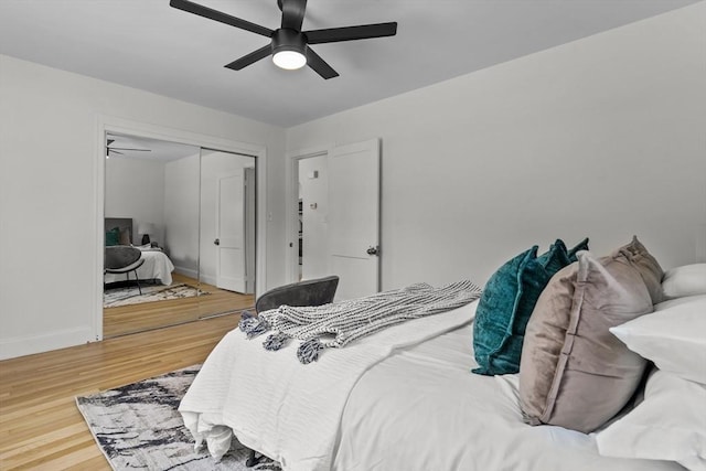 bedroom featuring baseboards, a ceiling fan, wood finished floors, and a closet