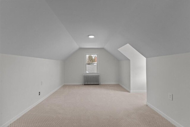 bonus room with light colored carpet, vaulted ceiling, radiator heating unit, and baseboards