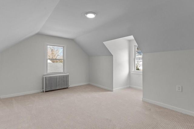 additional living space with lofted ceiling, radiator heating unit, carpet flooring, and plenty of natural light