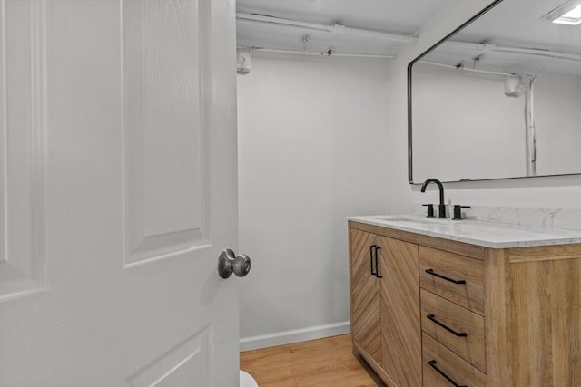 bathroom with baseboards, wood finished floors, and vanity
